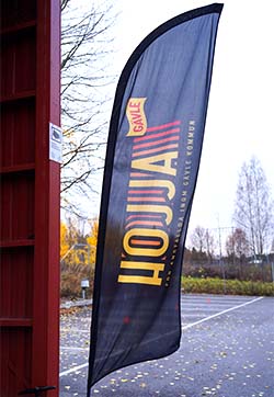En svart flagga med gul text där det står "Hojja".